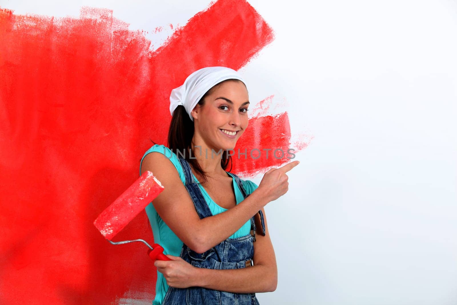 Young woman painting house wall in red