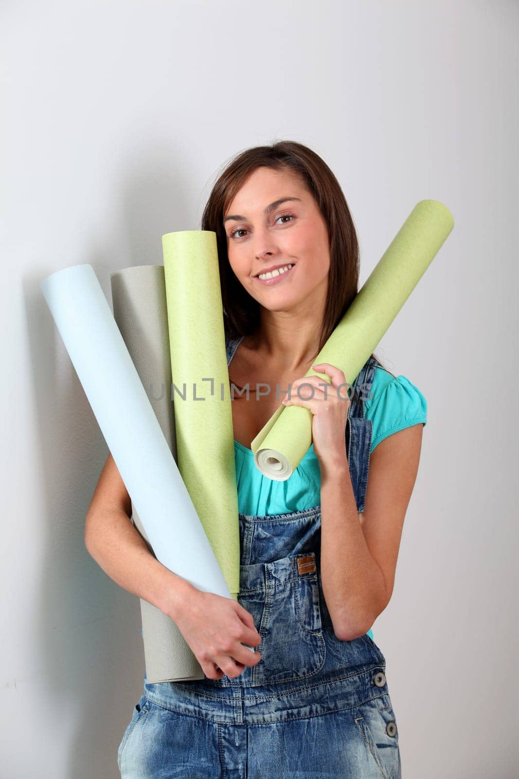 Beautiful young woman holding wallpaper rolls