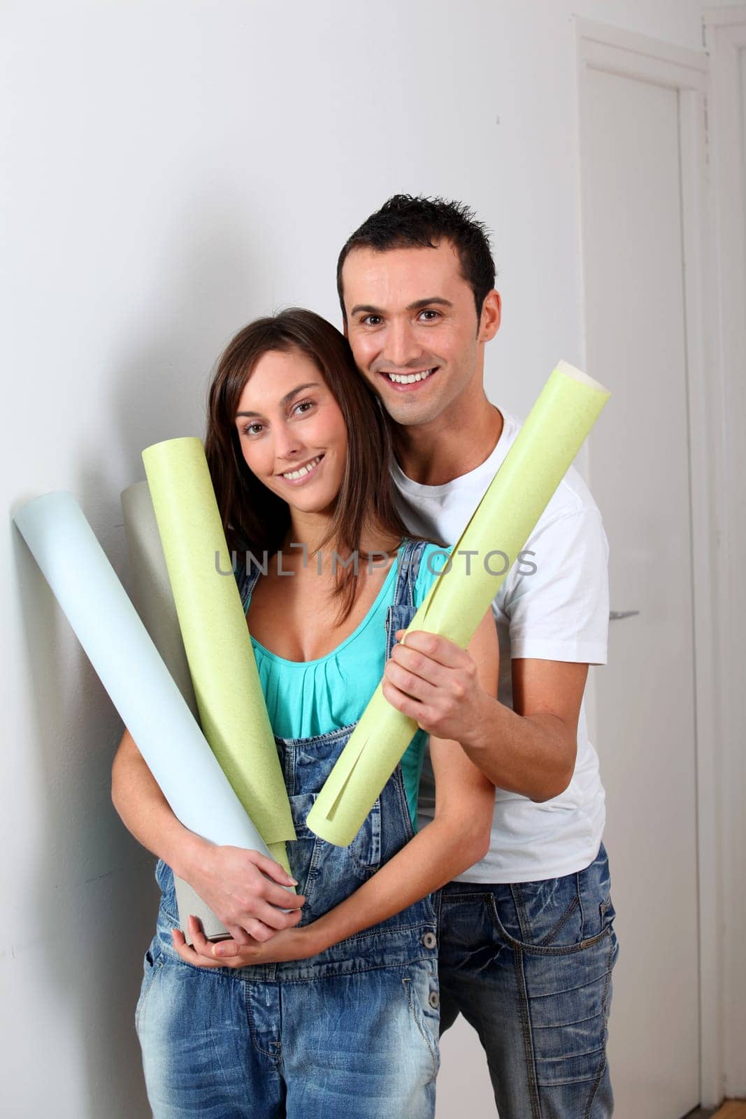 Closeup of young couple holding wallpaper rolls