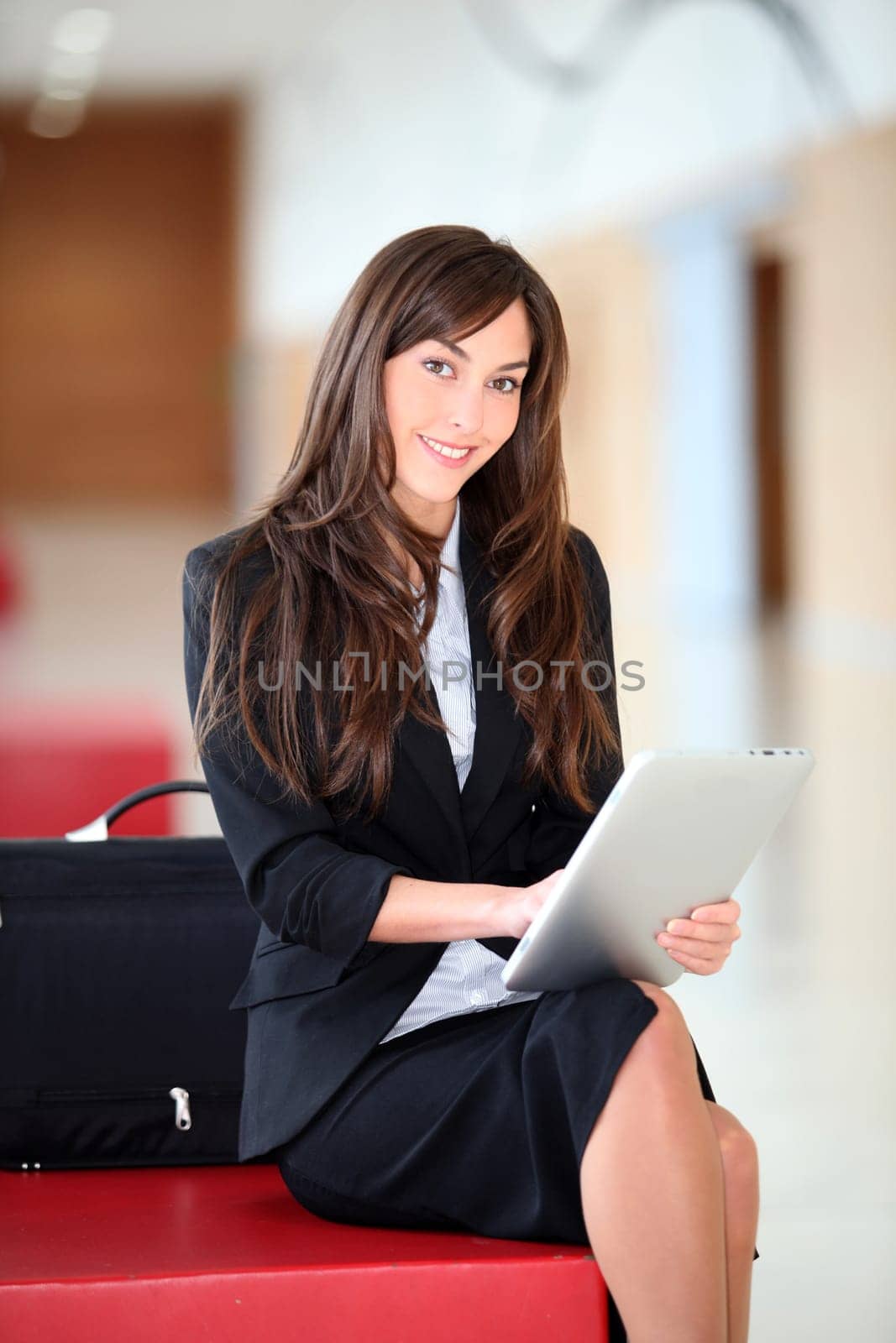 Businesswoman sitting in hall with electronic pad