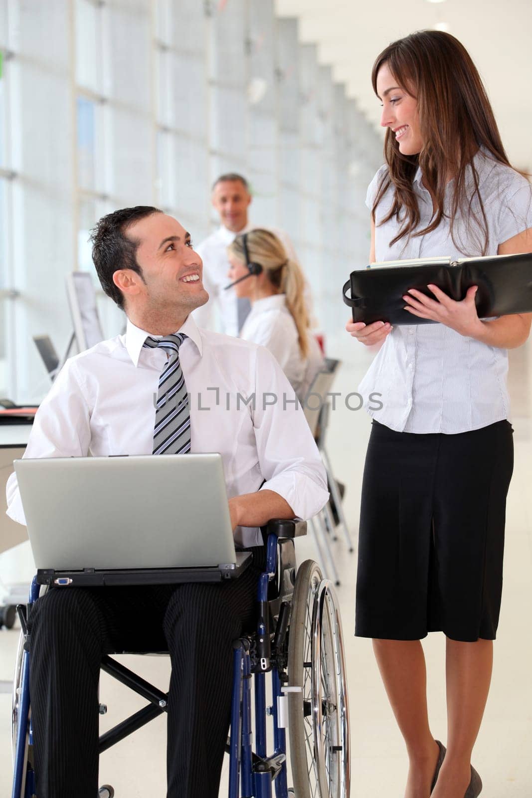 Businessman in wheelchair with assistant in office