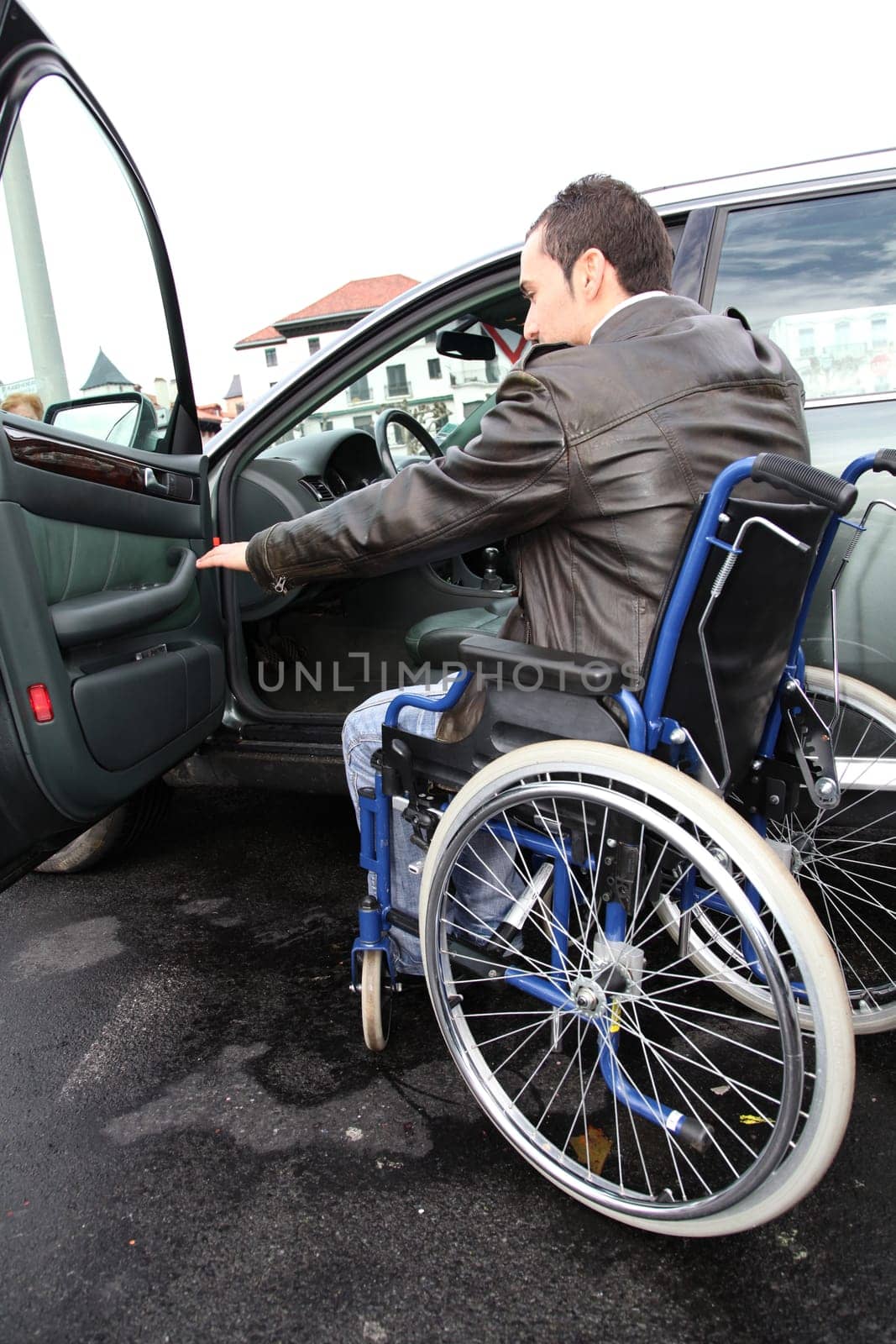 Young man in wheelchair getting in his car