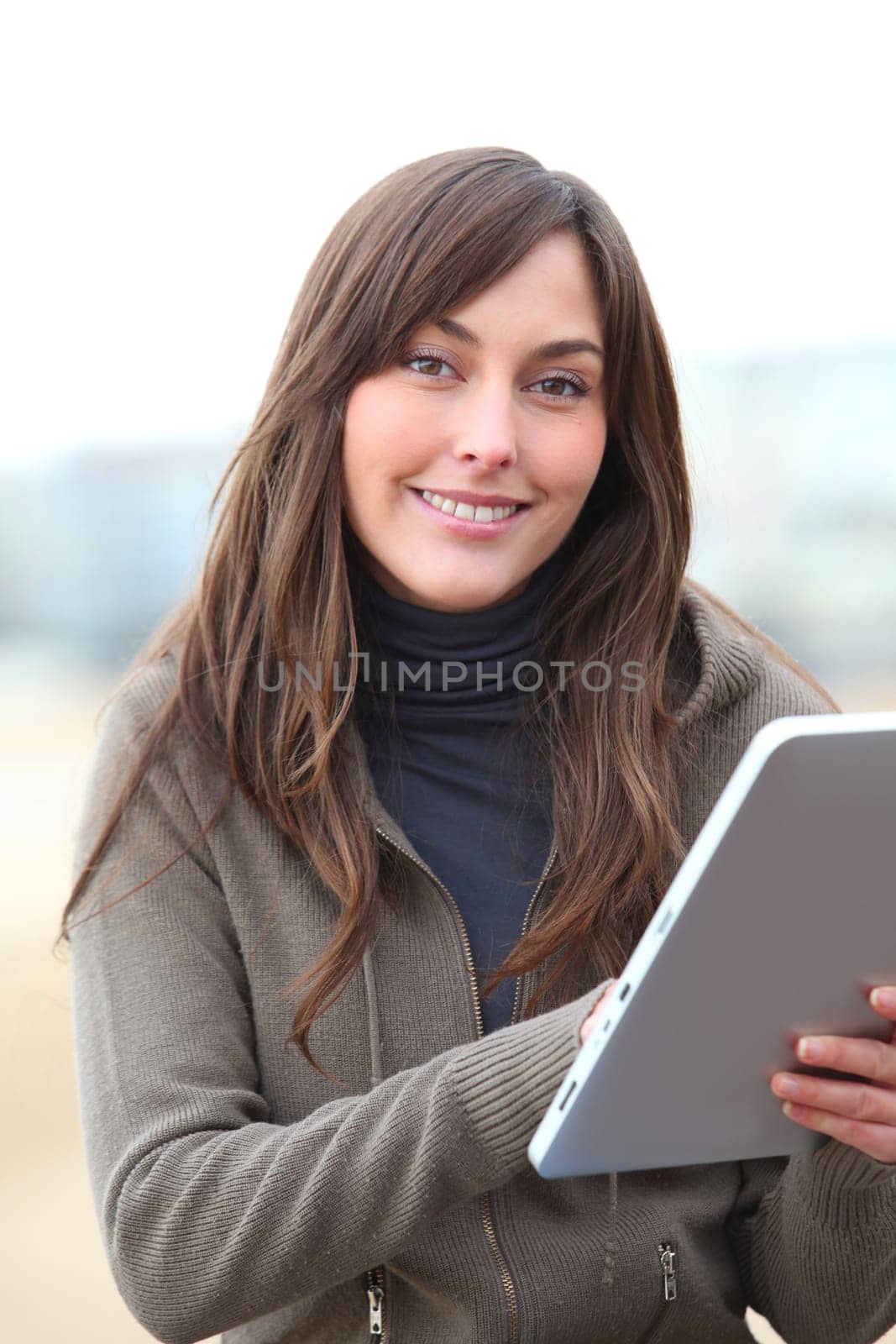 Young woman using electronic pad by the beach in winter