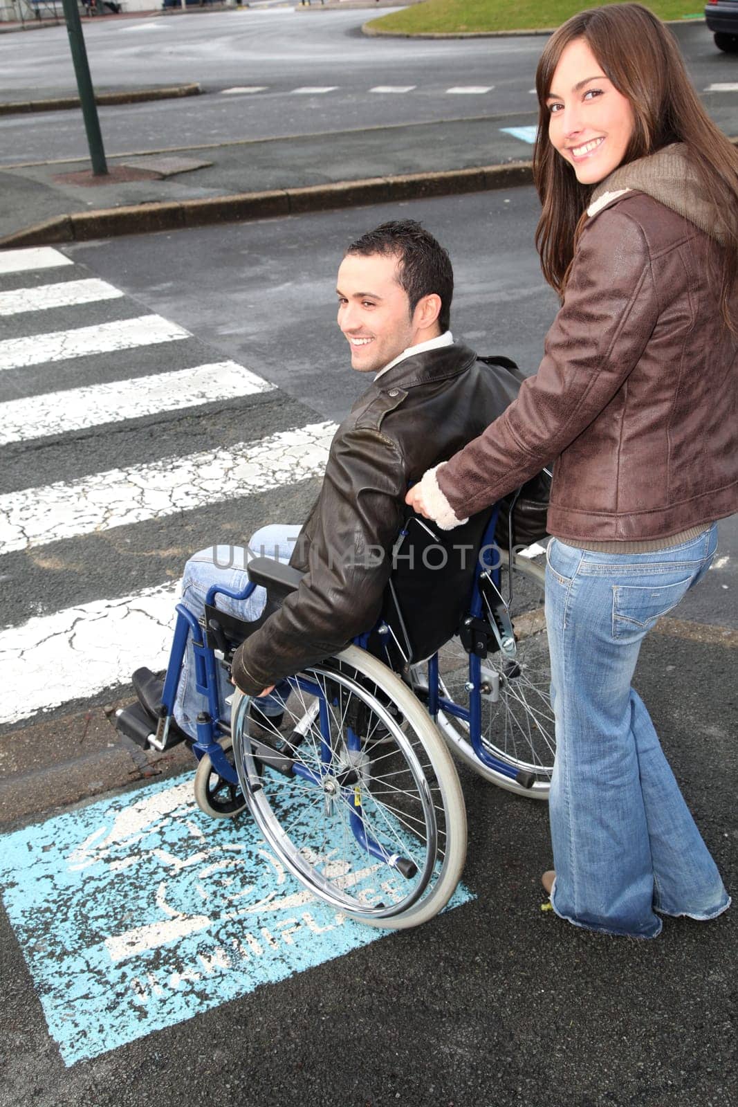 Woman helping friend in wheelchair cross the street