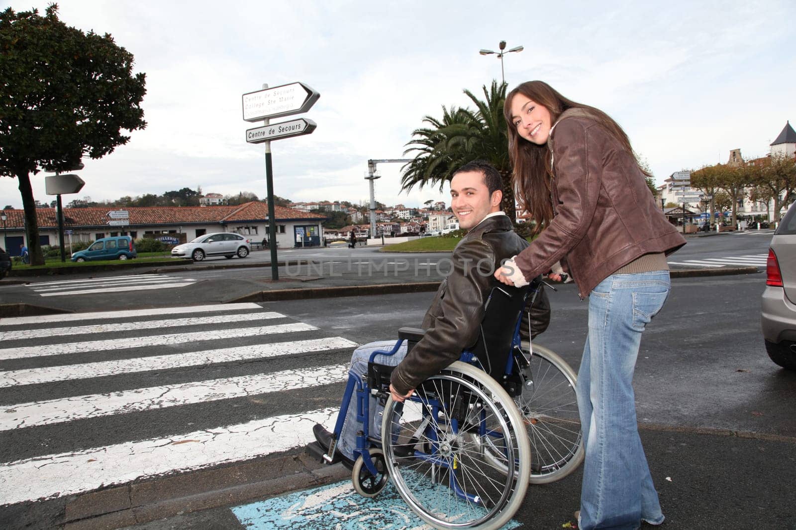 Woman helping friend in wheelchair cross the street