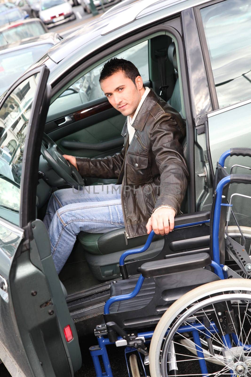 Young man in wheelchair getting in his car