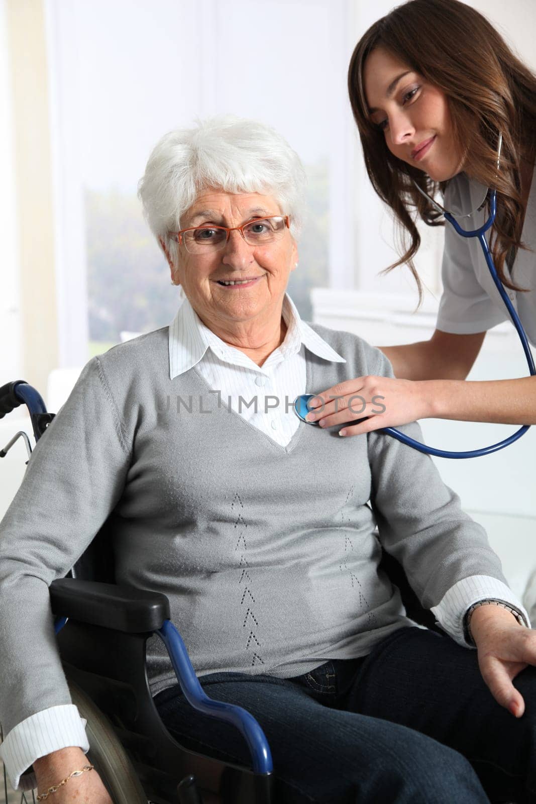 Elderly woman in wheelchair with nurse at home