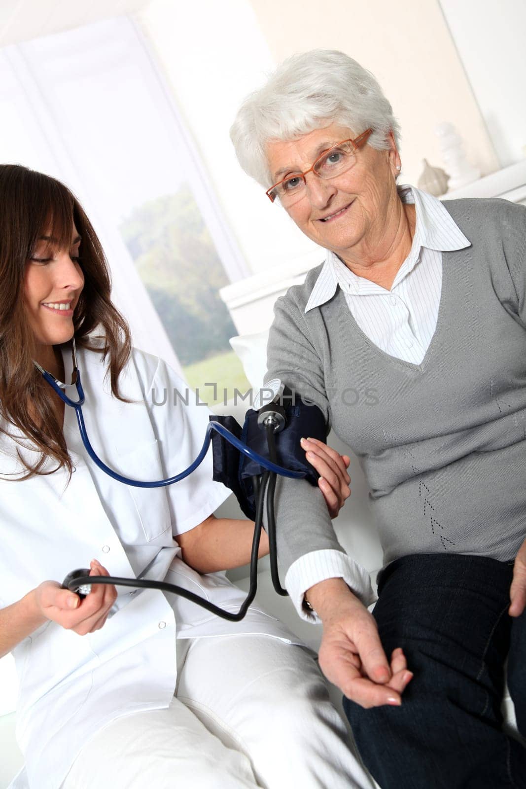 Closeup of nurse checking senior woman blood pressure
