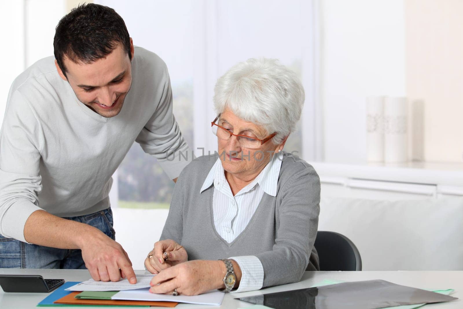 Young man helping elderly woman with paperwork