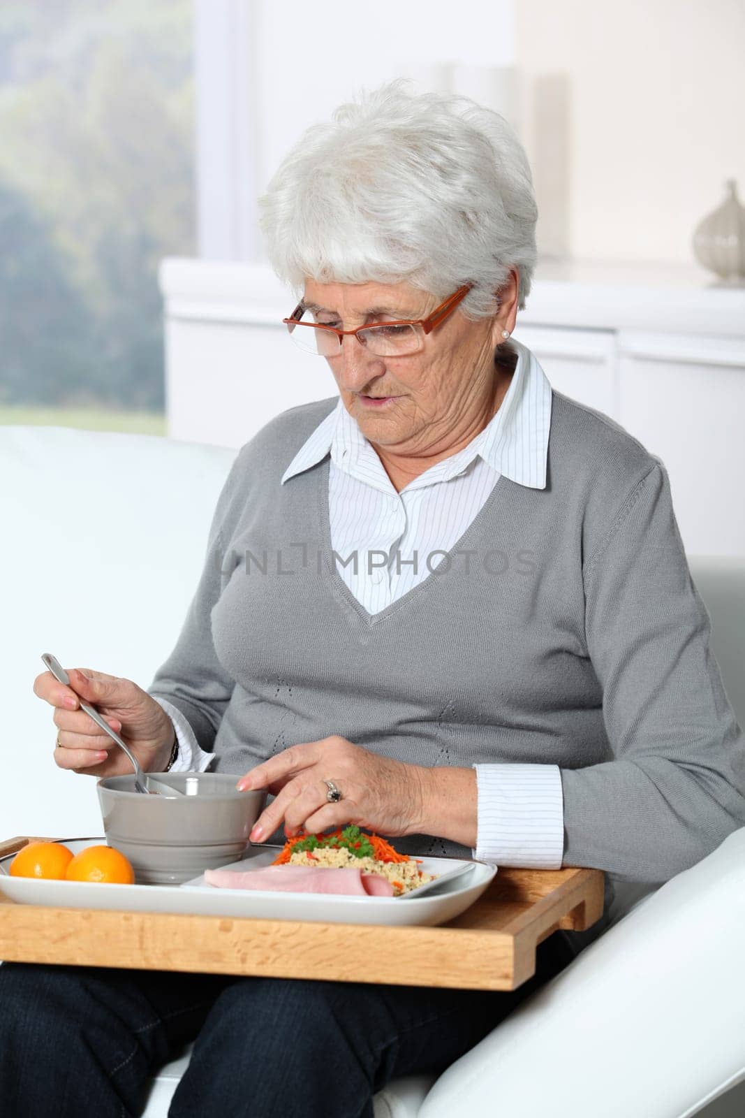 Elderly woman sitting in sofa  with lunch tray
