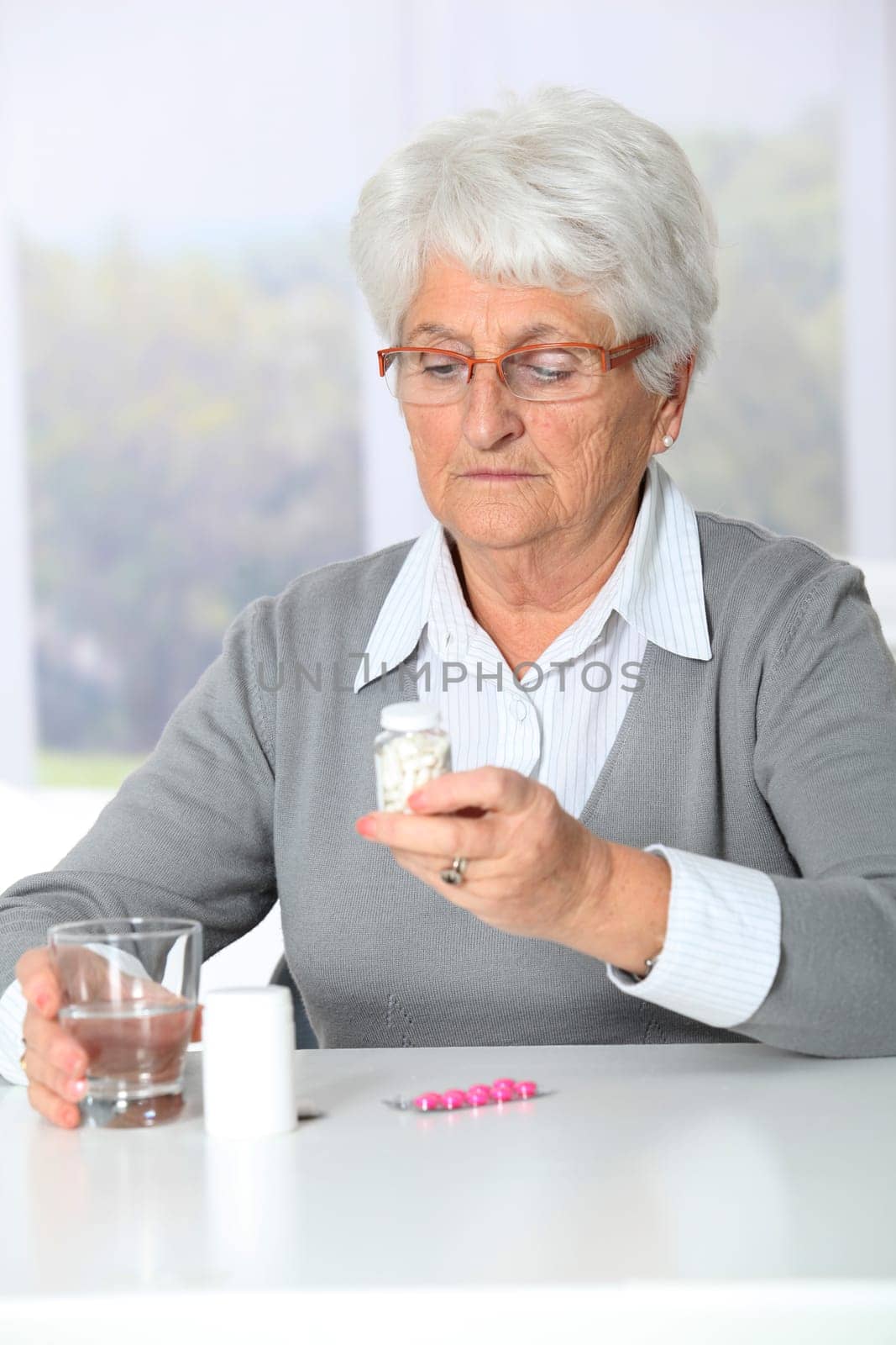 Closeup of old woman looking at medicine bottles