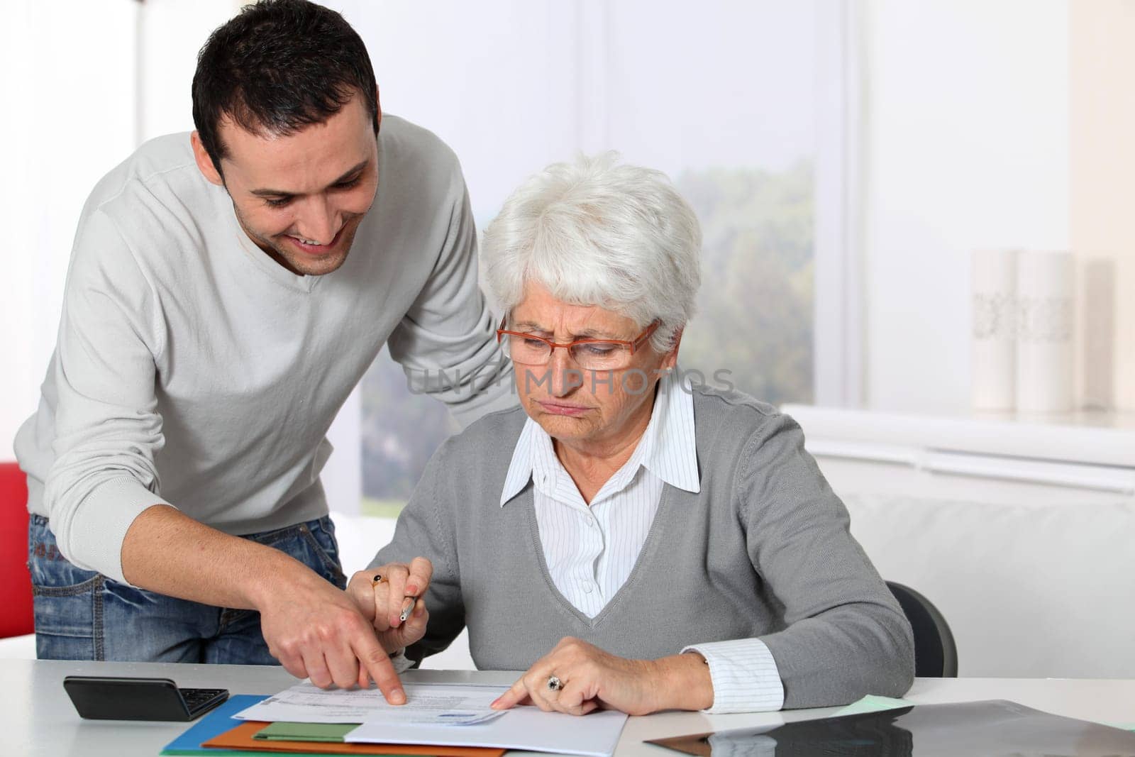 Young man helping elderly woman with paperwork