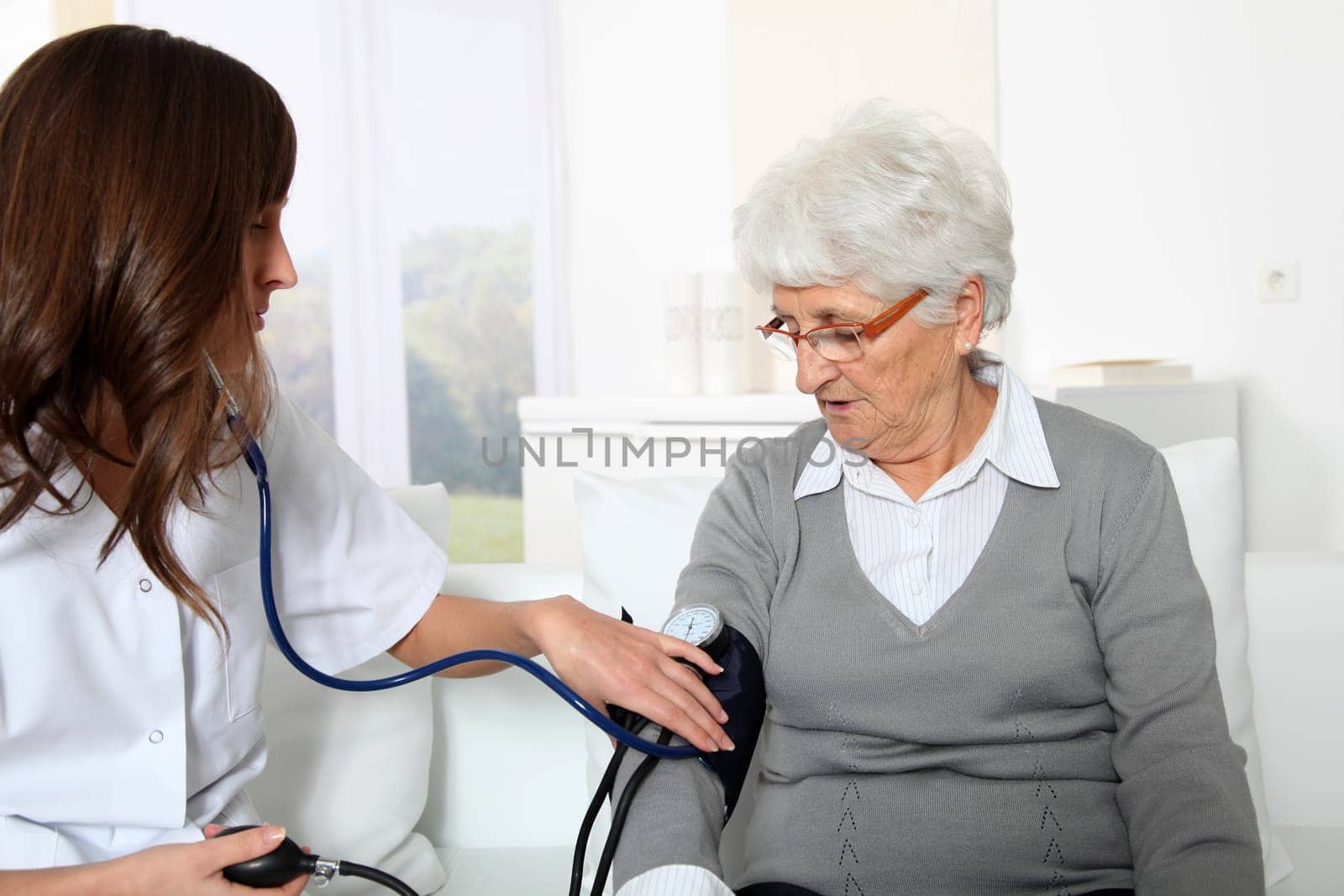 Closeup of nurse checking senior woman blood pressure