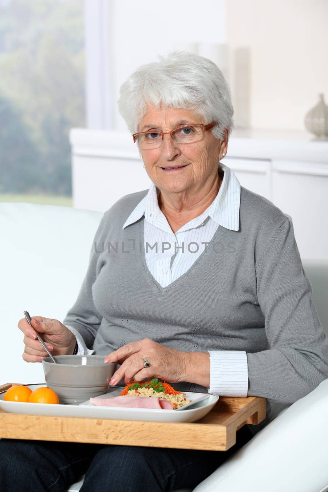 Elderly woman sitting in sofa  with lunch tray