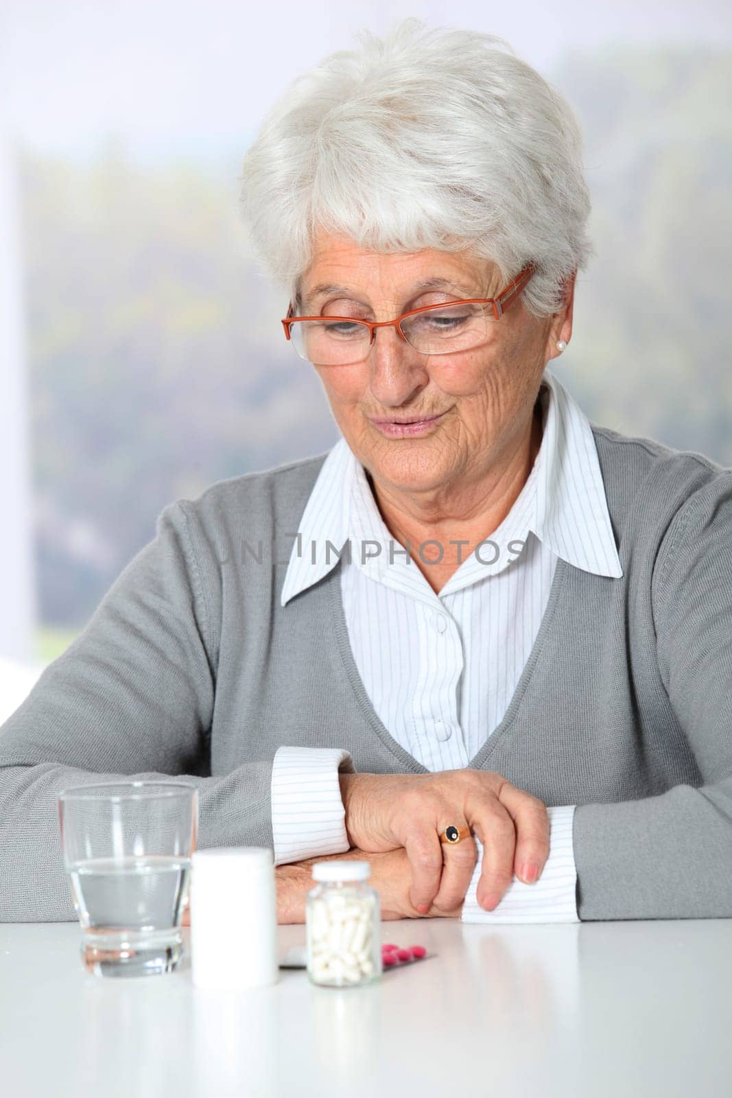 Closeup of old woman looking at medicine bottles
