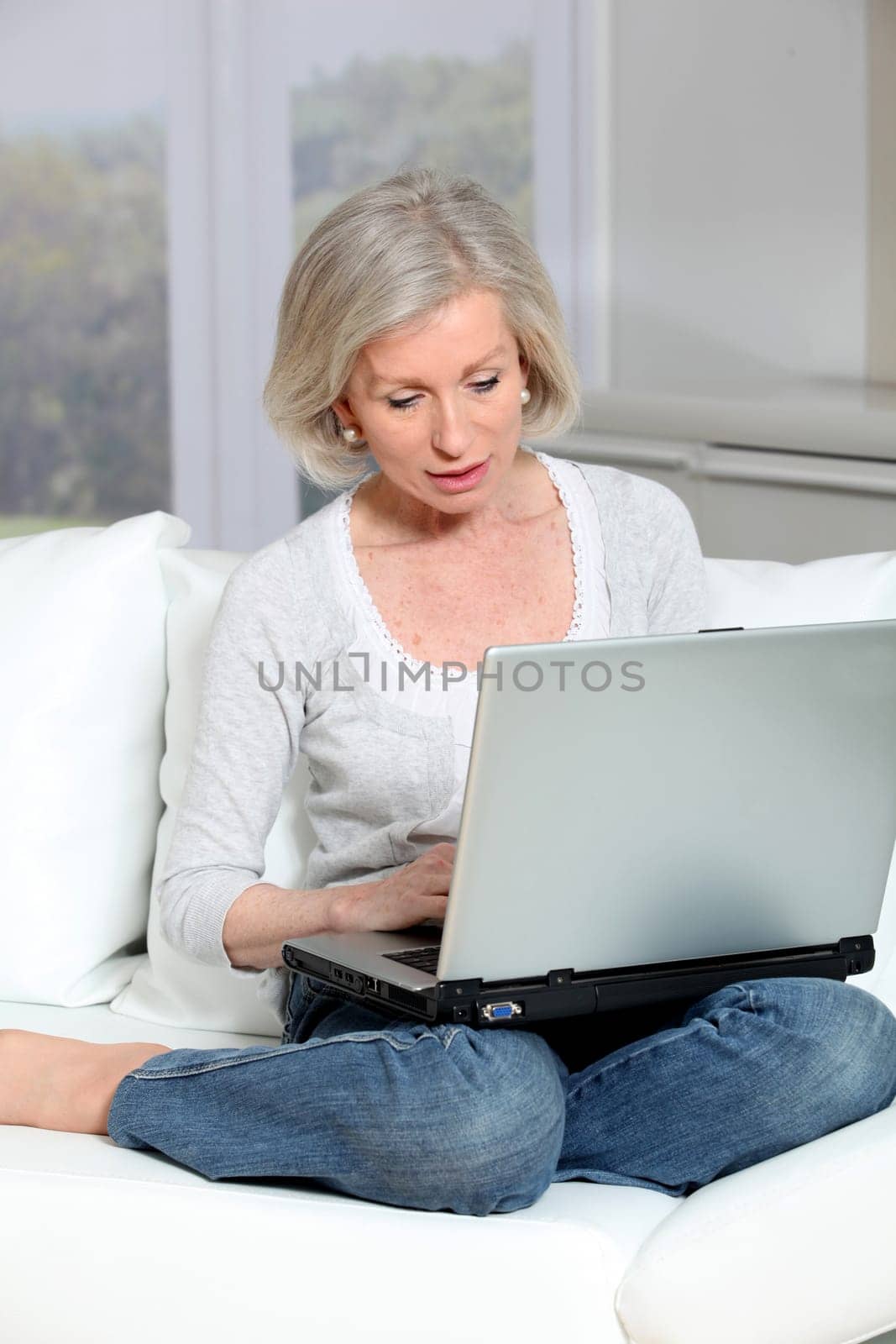 Senior woman sitting in sofa with laptop computer