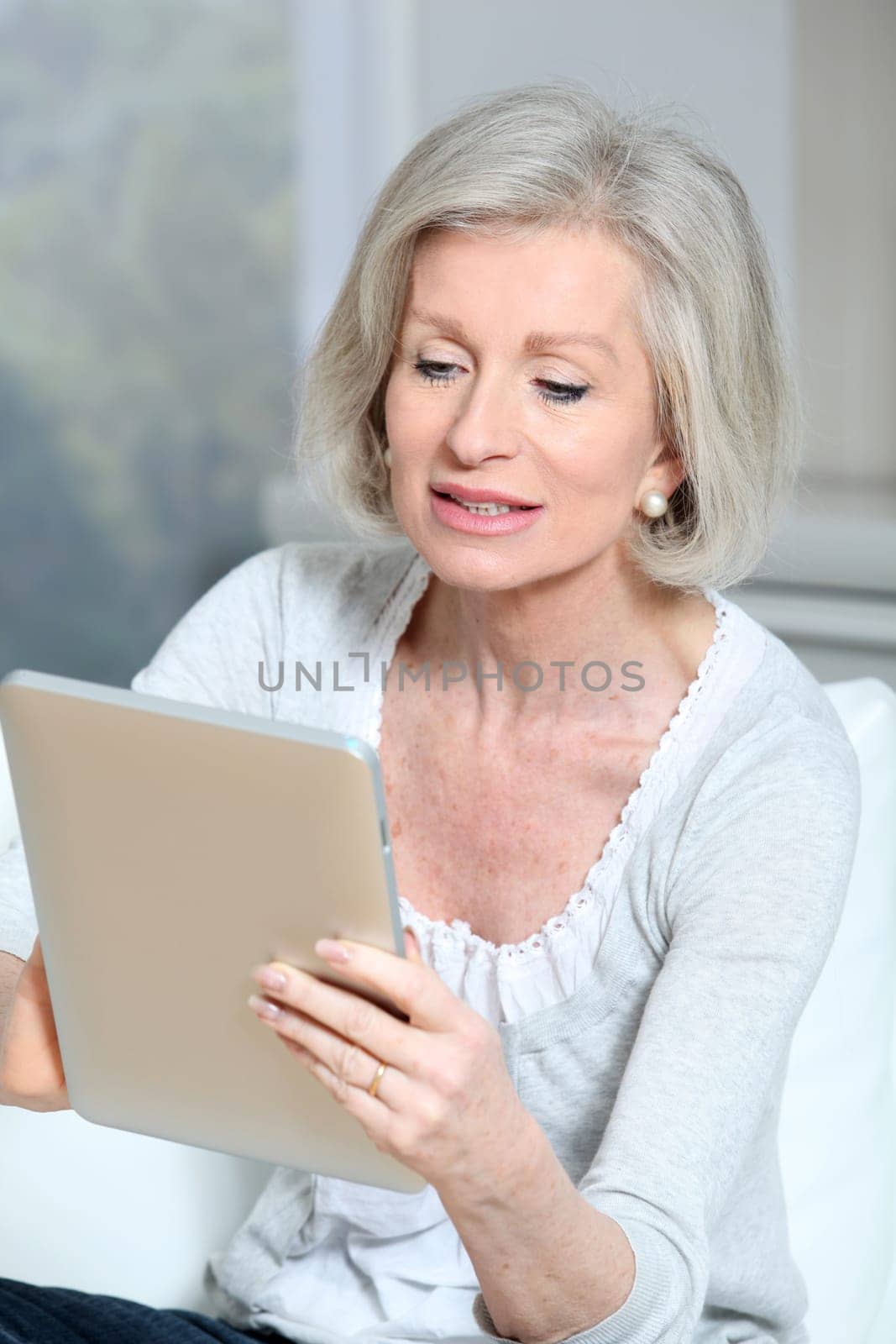 Closeup of senior woman sitting on sofa with electronic pad