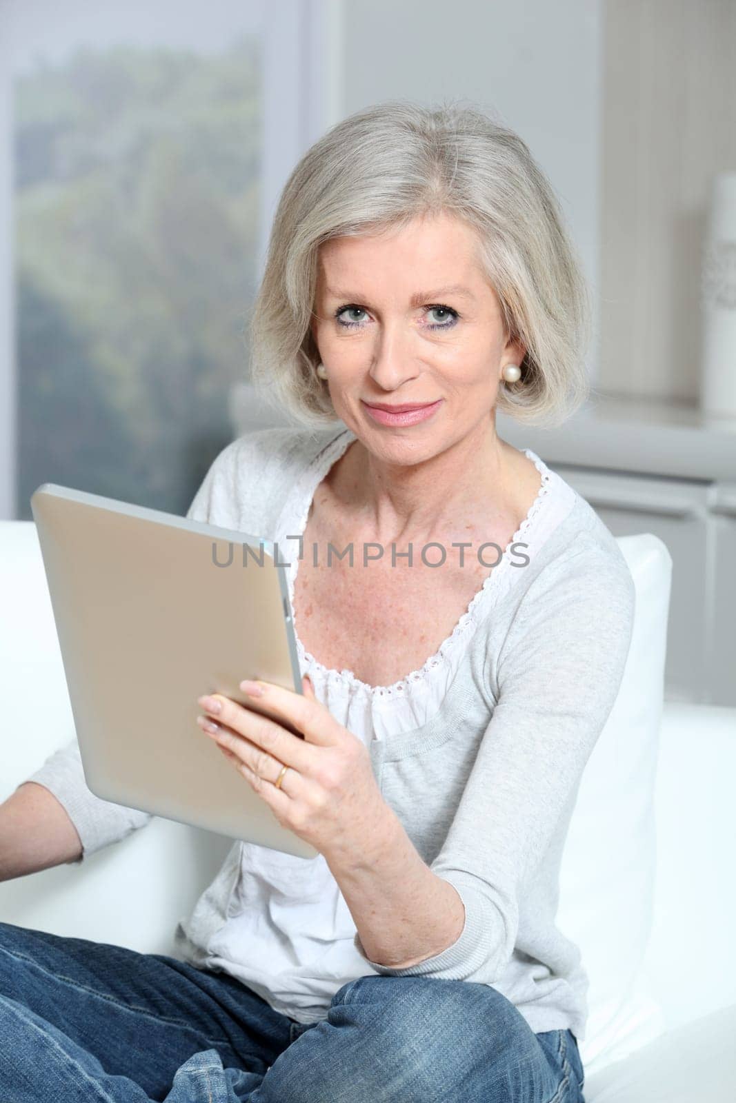 Closeup of senior woman sitting on sofa with electronic pad
