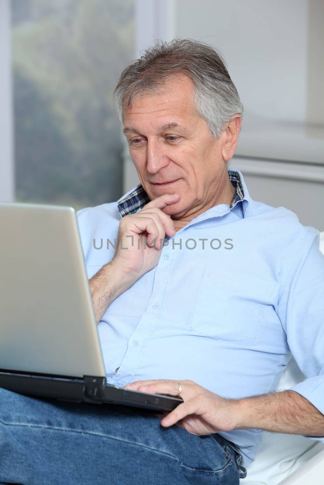 Senior man in sofa with laptop computer
