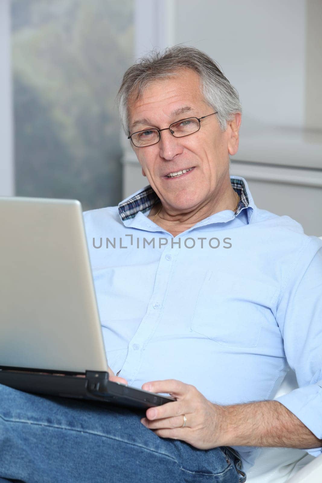 Senior man in sofa with laptop computer