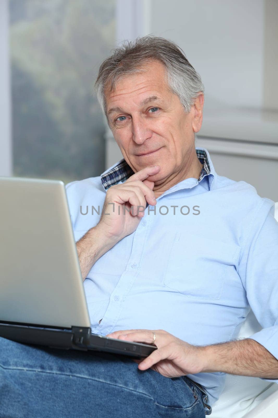 Senior man in sofa with laptop computer