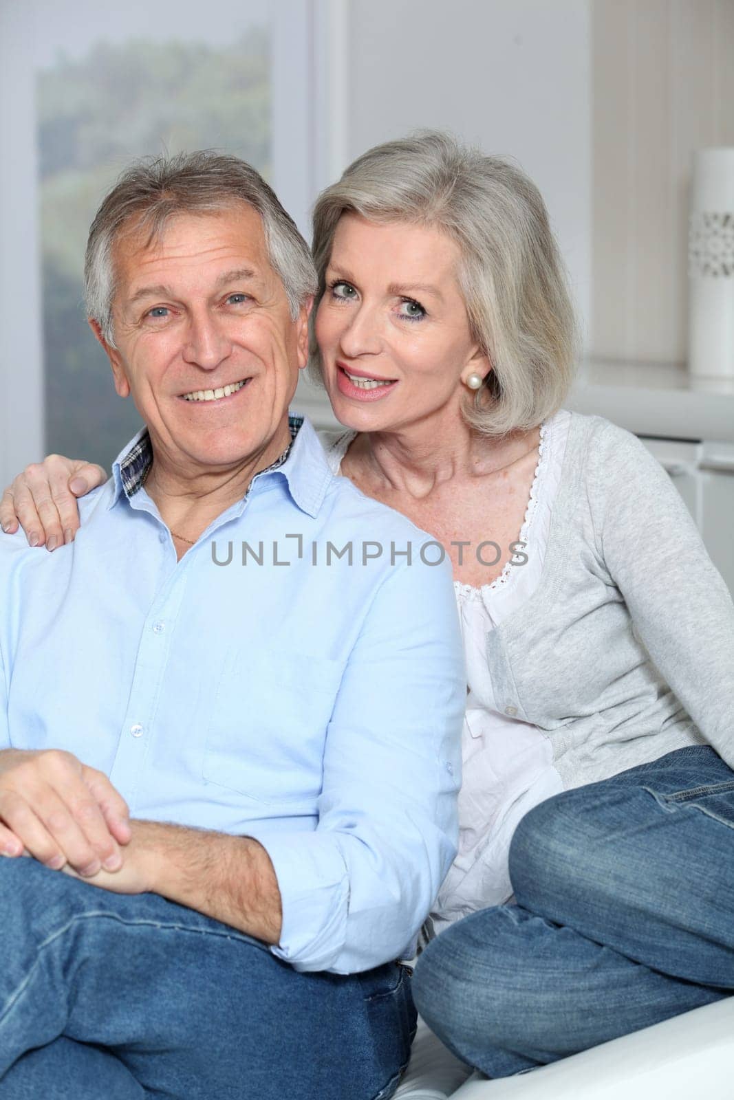 Portrait of happy senior couple sitting in sofa