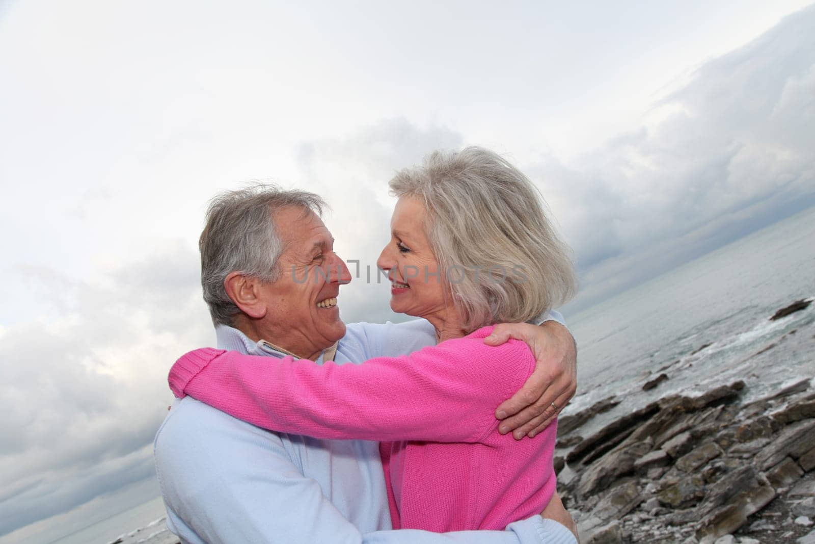 Happy senior couple embracing each other by the sea