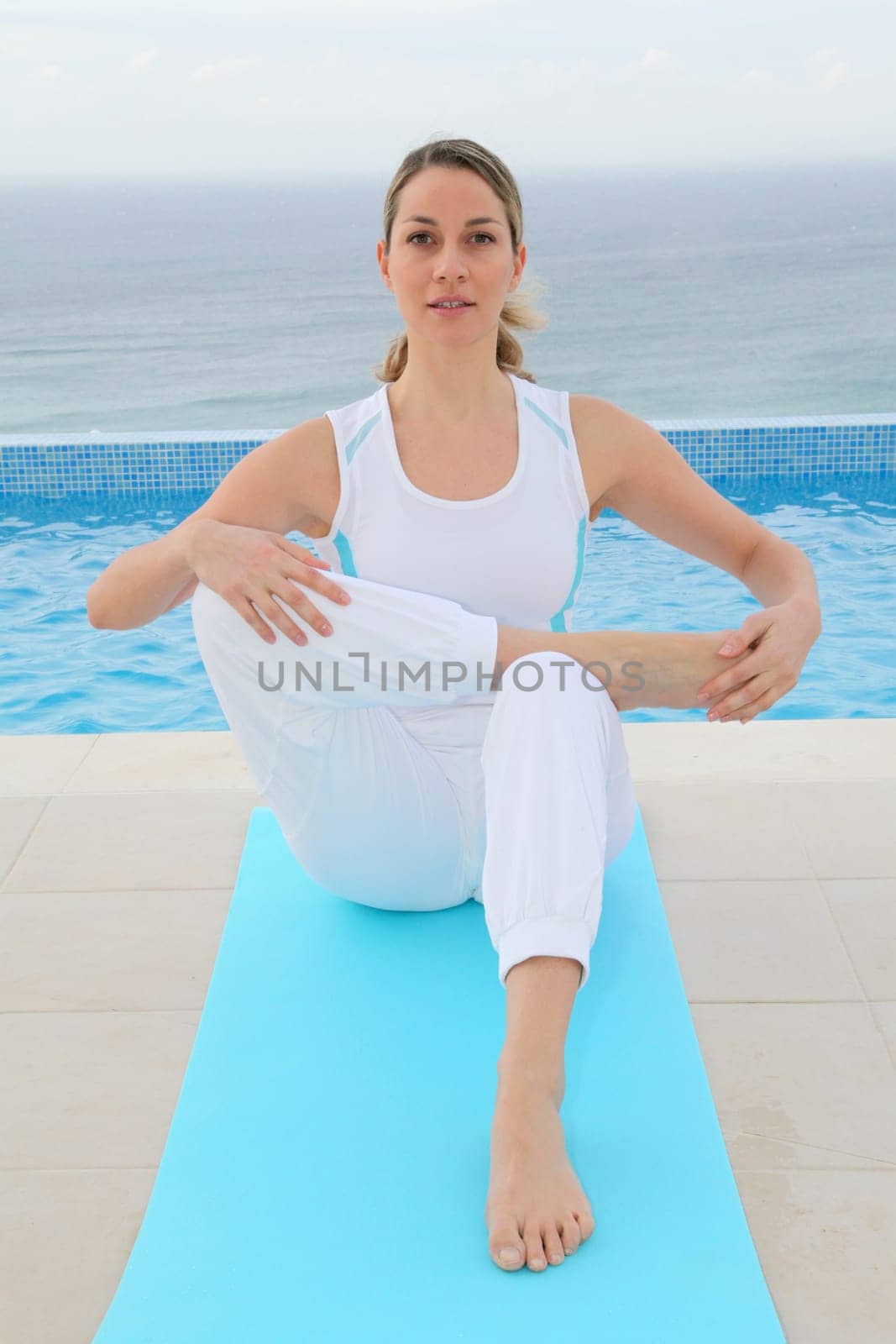 Woman doing exercises by a swimming-pool