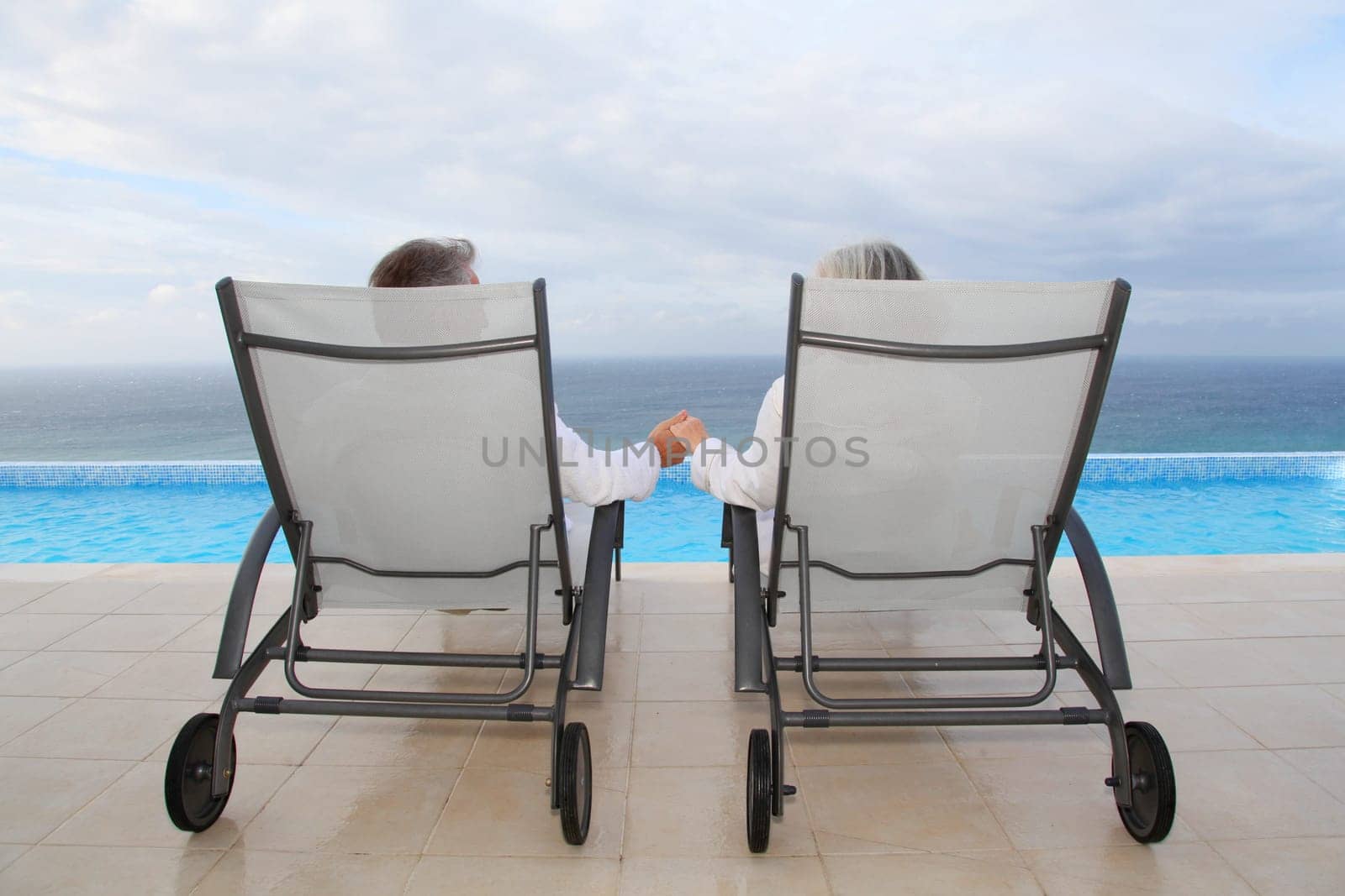 Senior couple relaxing in long chairs