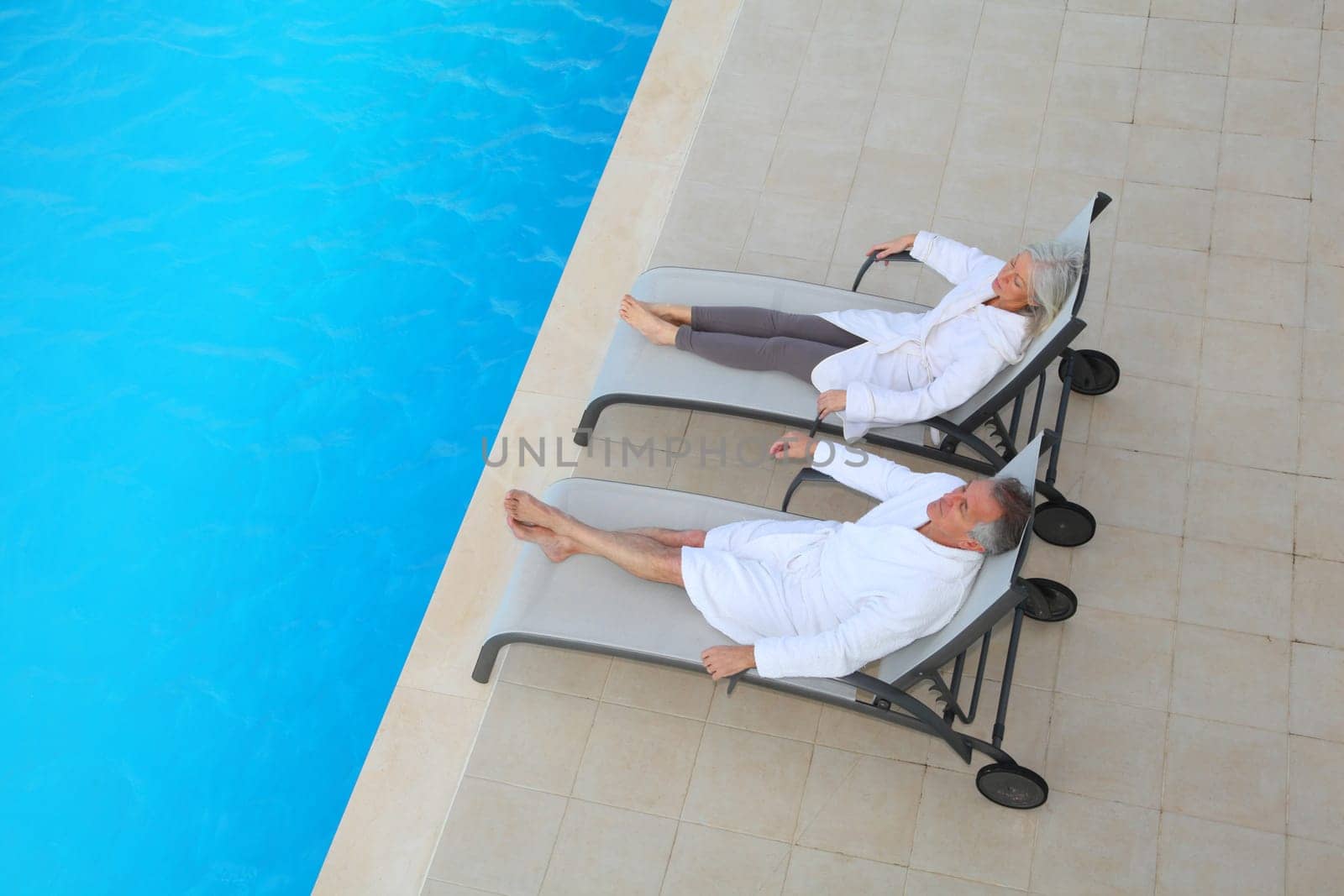 Senior couple relaxing in long chairs