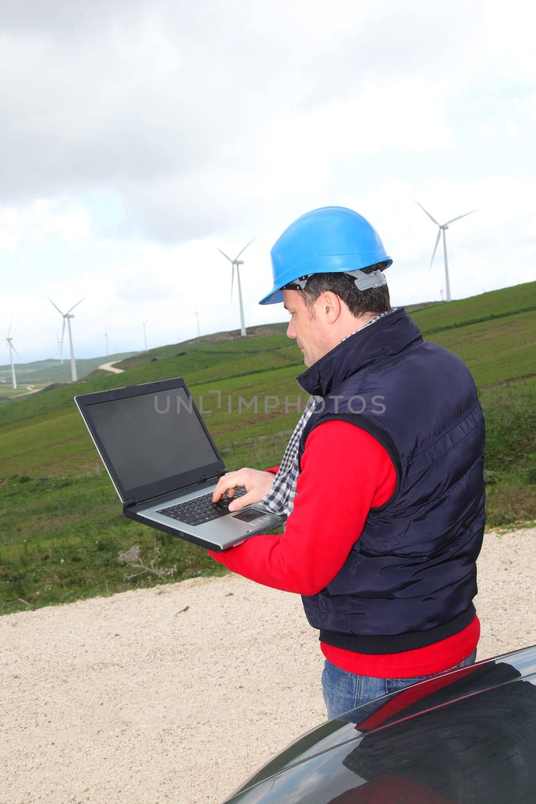 Engineer working on laptop computer in wind turbines field