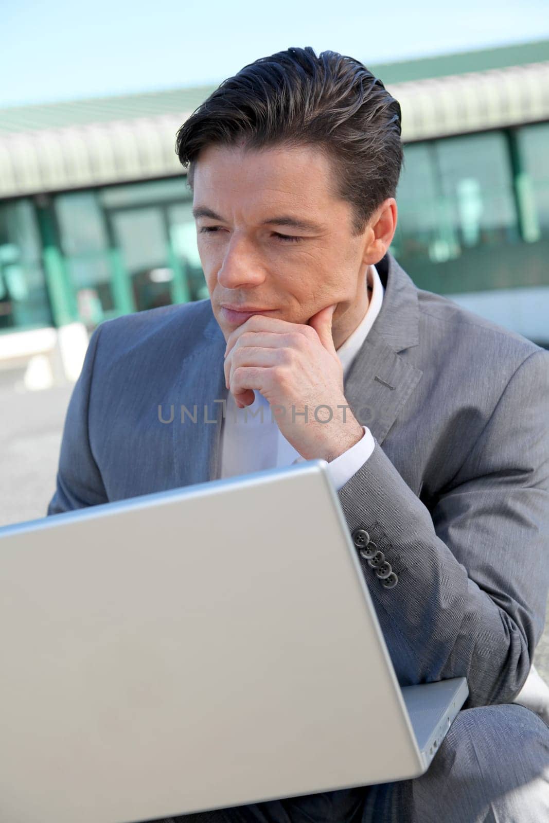 Businessman working on laptop computer by the airport