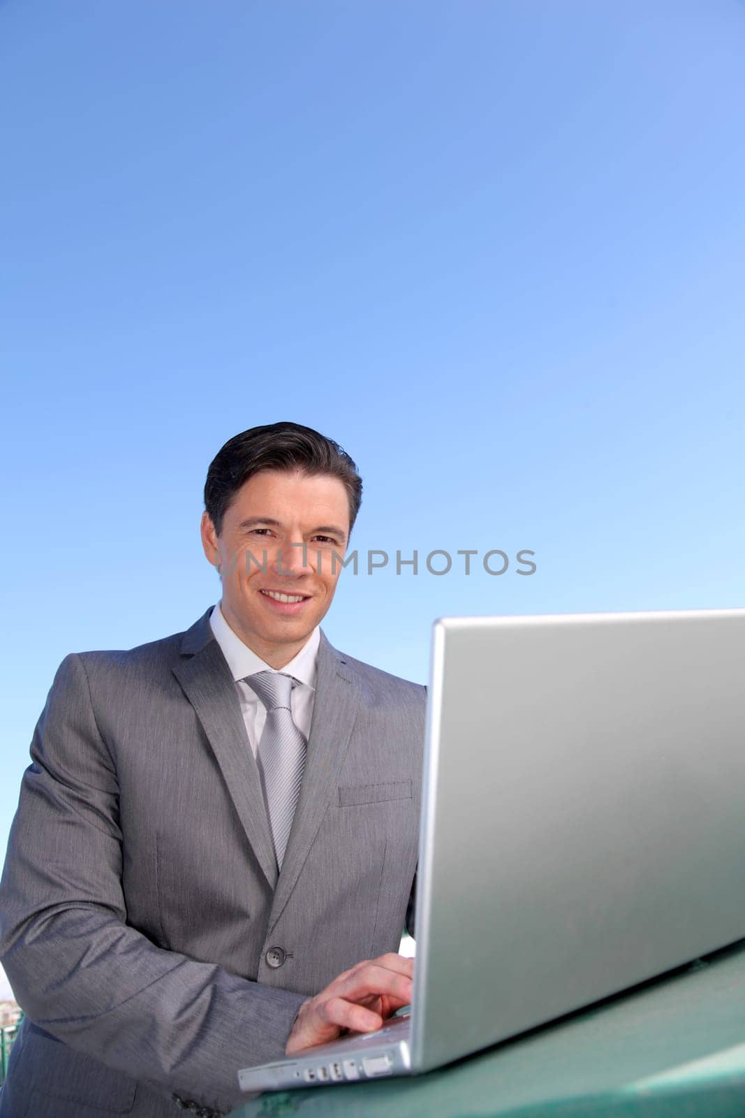 Smiling businessman working outside with laptop computer