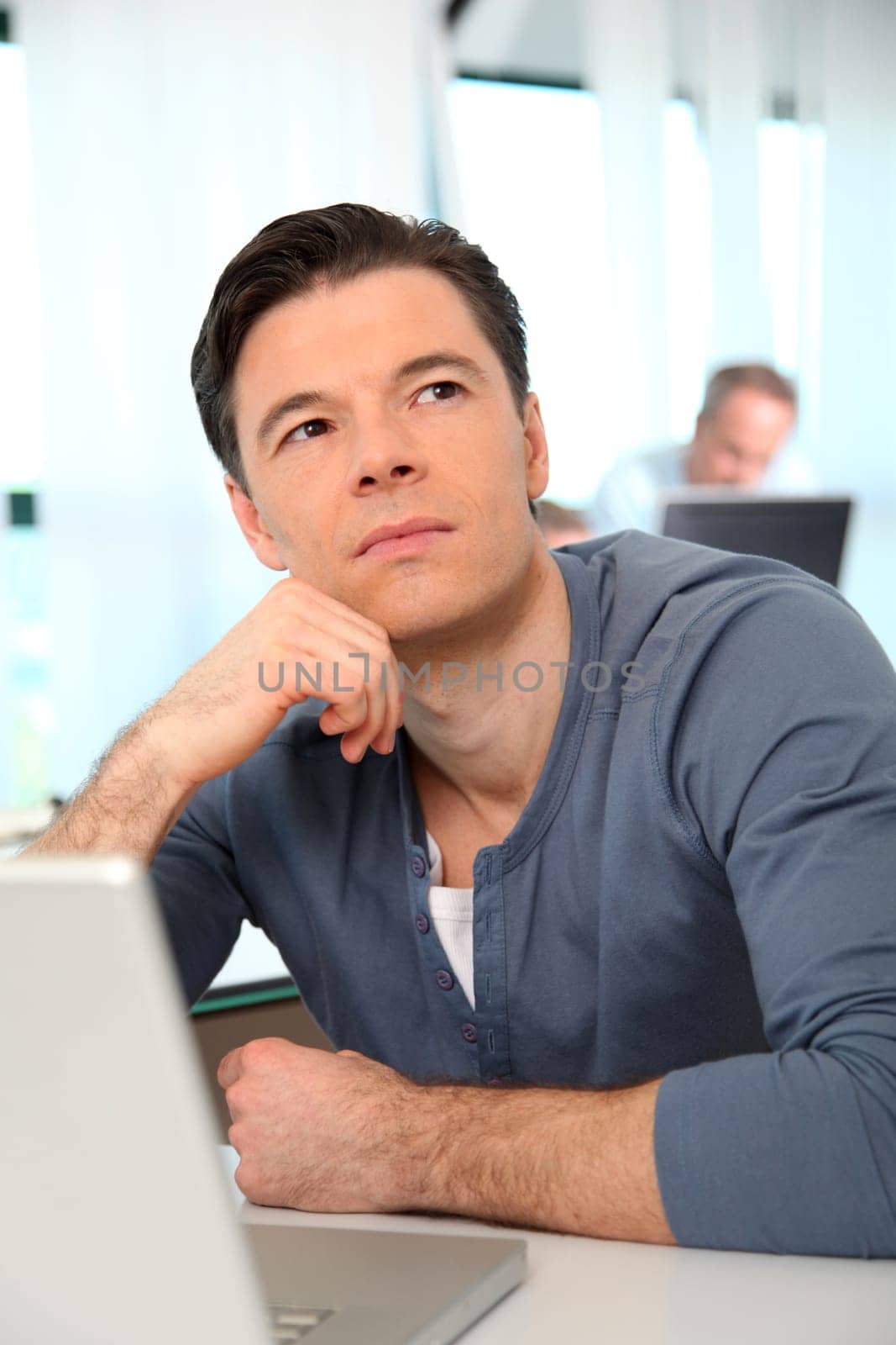 Office worker with exhausted look in front of computer