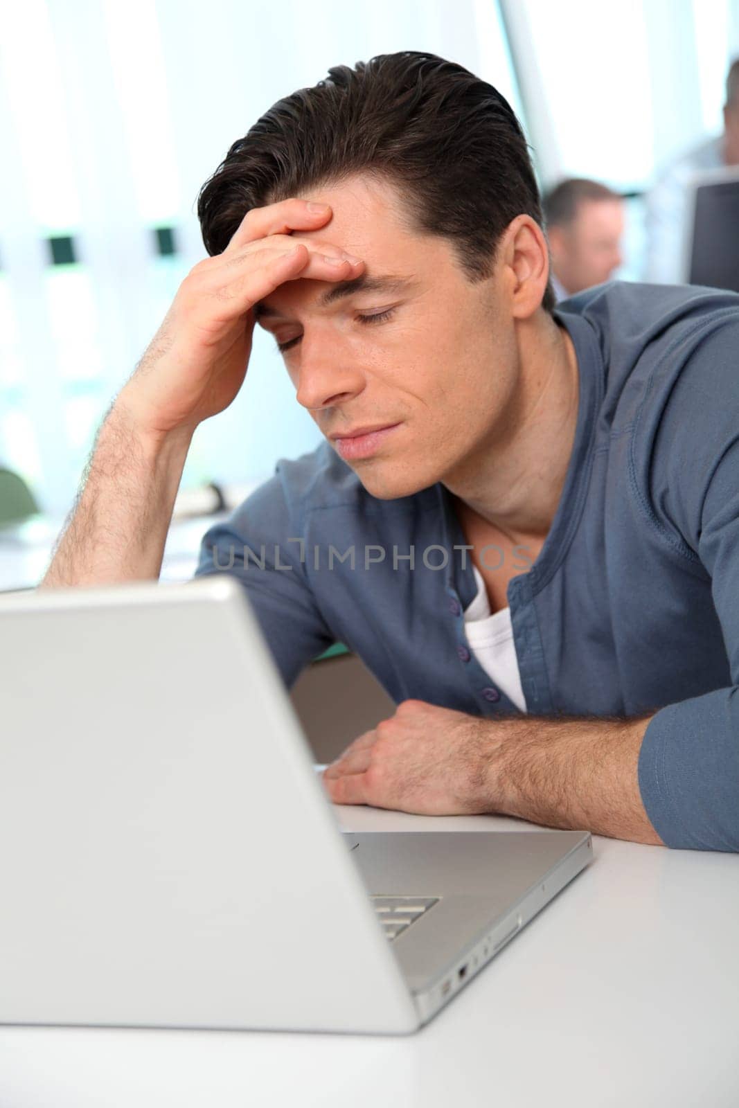 Office worker with exhausted look in front of computer