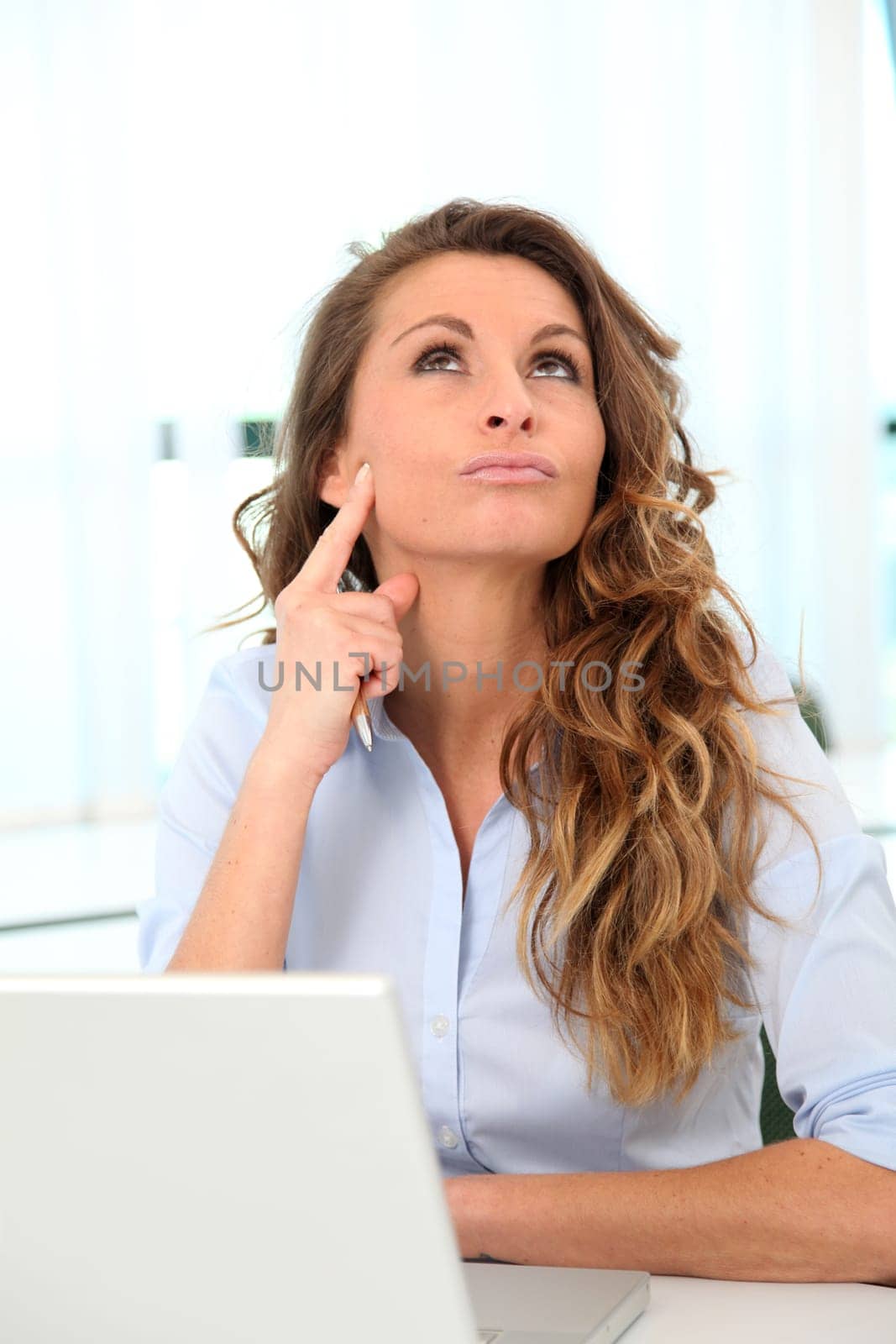 Office worker with toughtful look in front of laptop computer