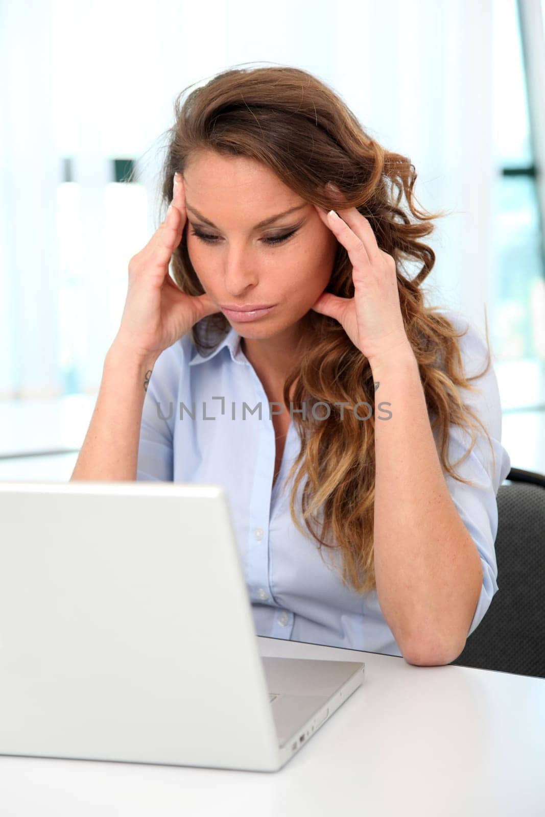 Office worker with desperate look in front of laptop