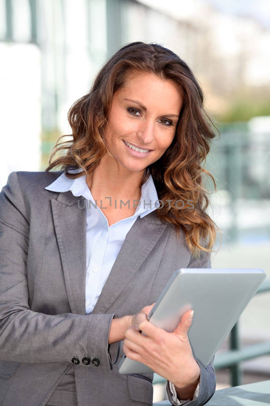 Smiling businesswoman using electronic tablet outside