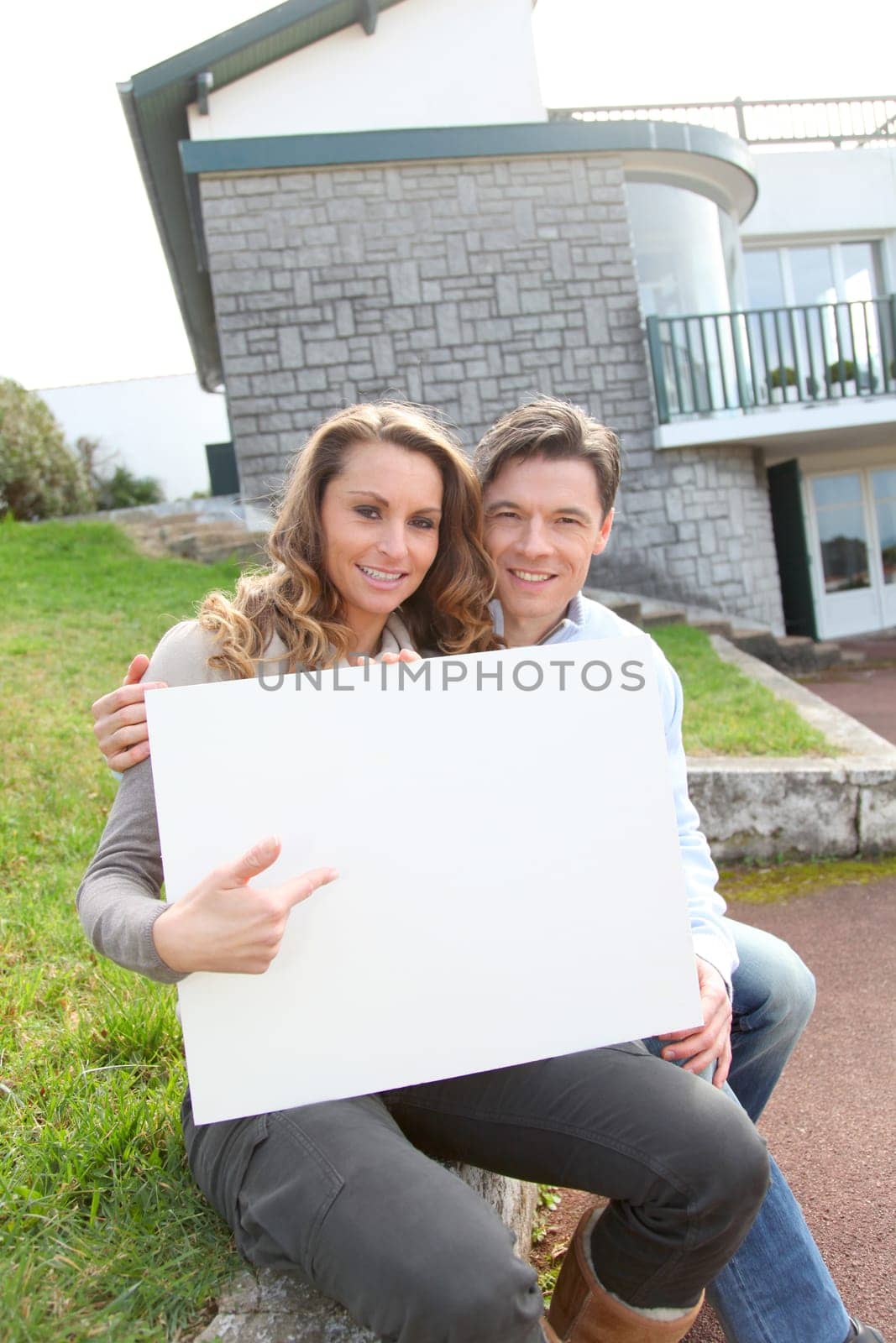 Couple holding whiteboard in front of their house