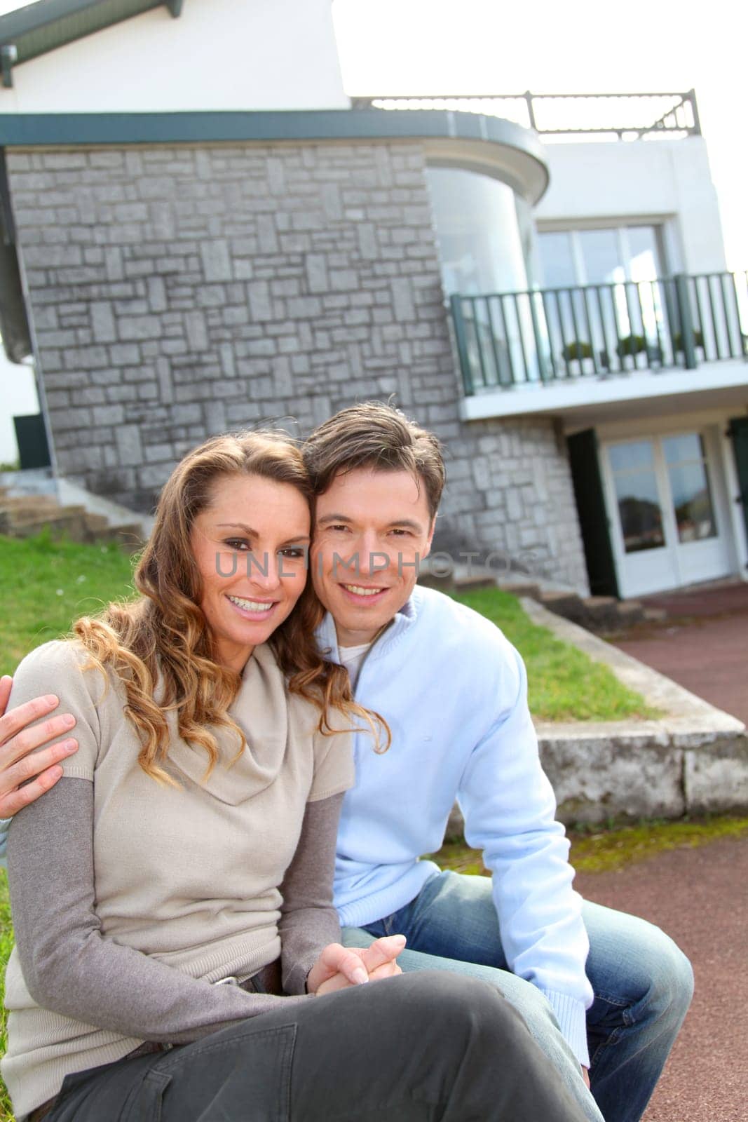Couple sitting in front of their new home
