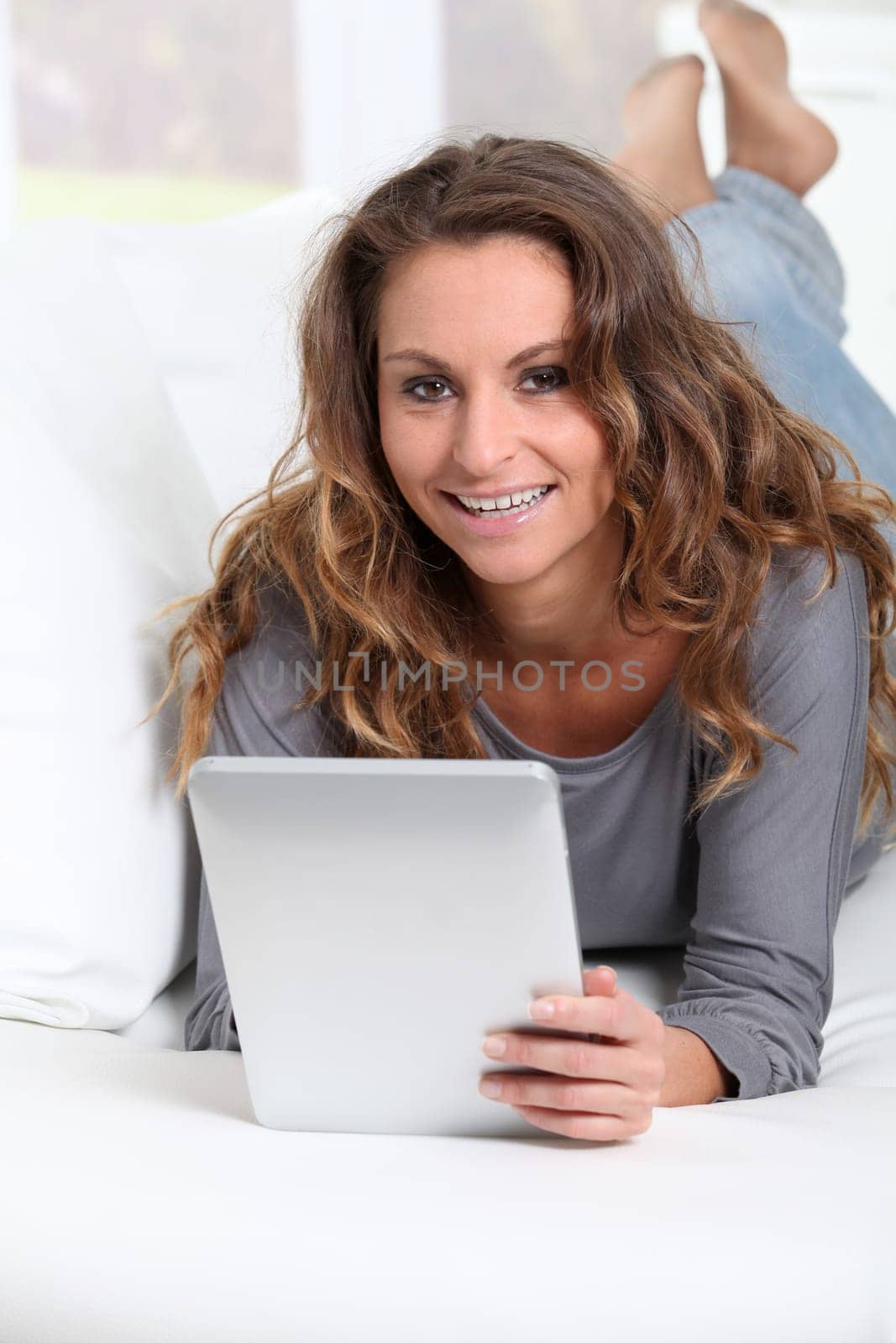 Beautiful woman laying on sofa with electronic tablet