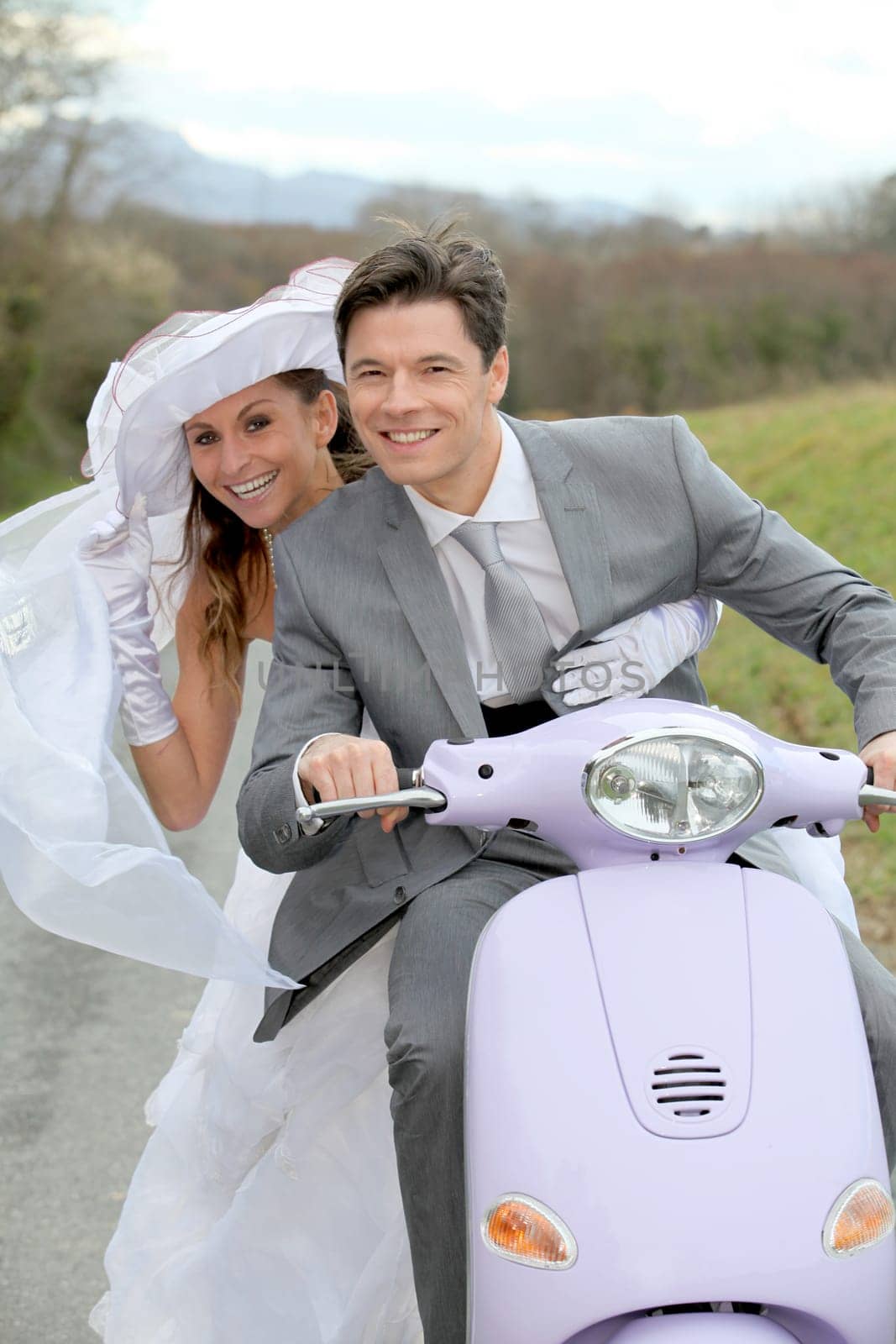 Married couple riding motorcycle on their wedding day