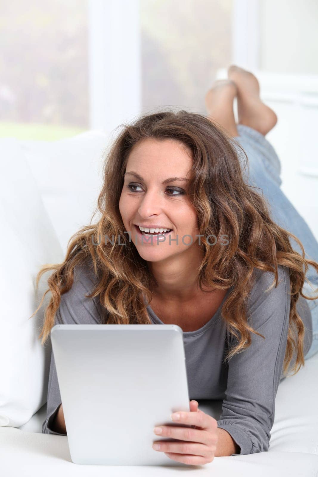 Beautiful woman laying on sofa with electronic tablet