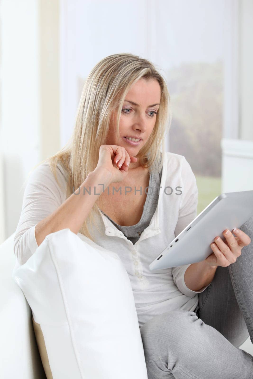 Blond woman using electronic tablet at home