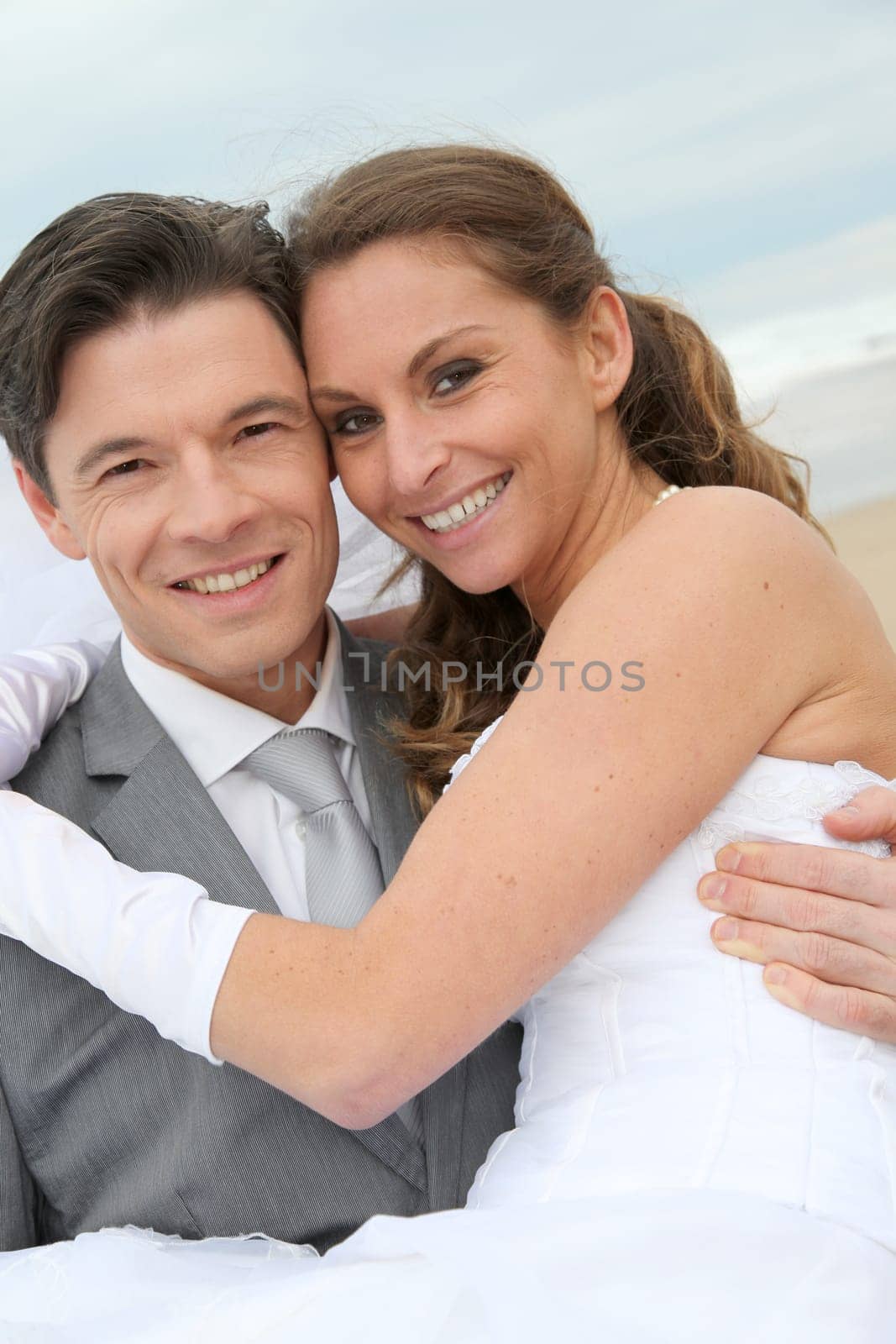 Groom holding bride in his arms at the beach