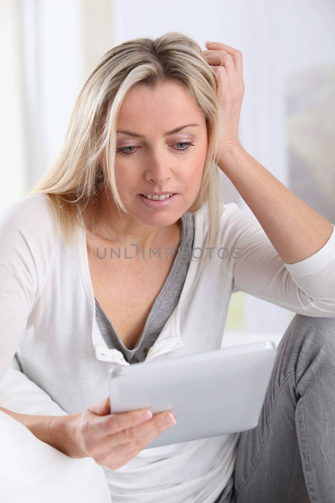 Blond woman using electronic tablet at home
