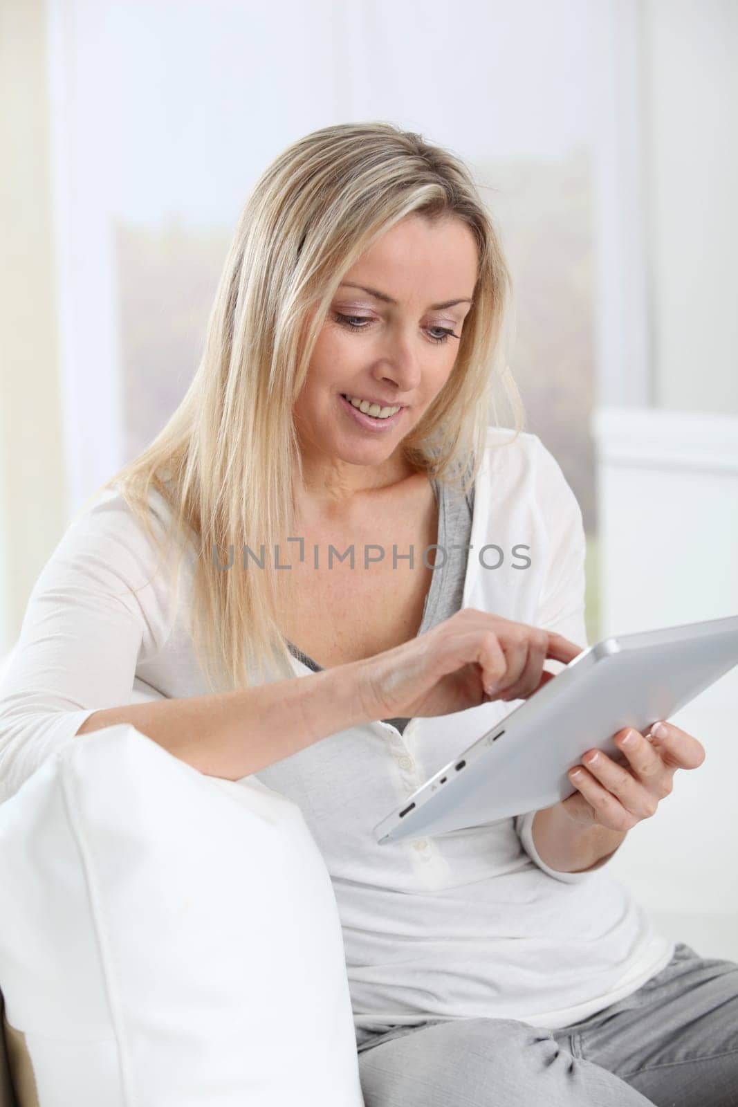 Blond woman using electronic tablet at home