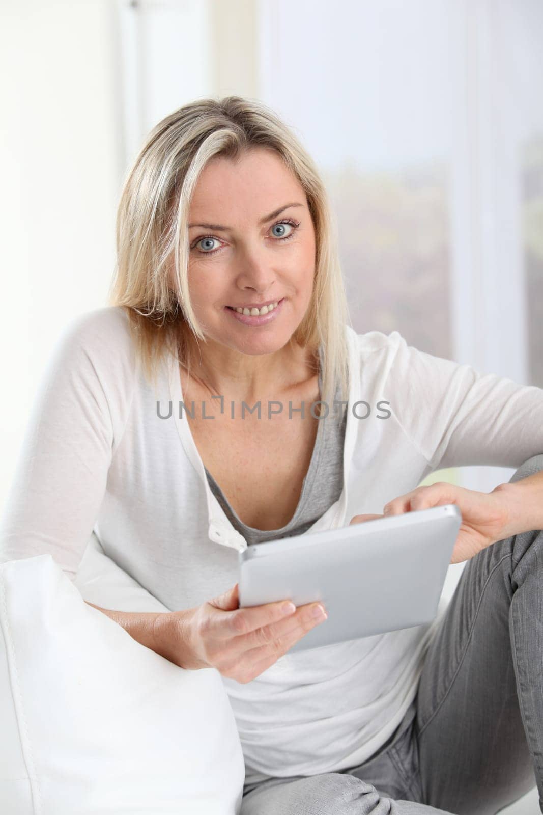 Blond woman using electronic tablet at home