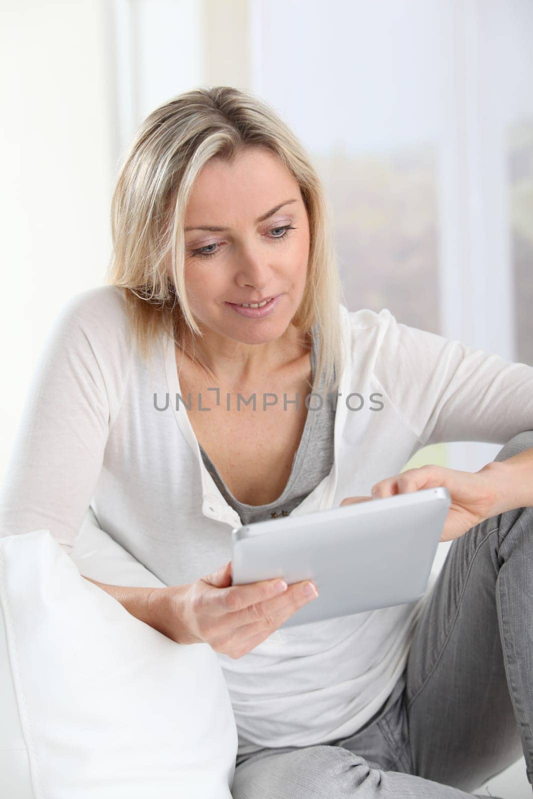 Blond woman using electronic tablet at home