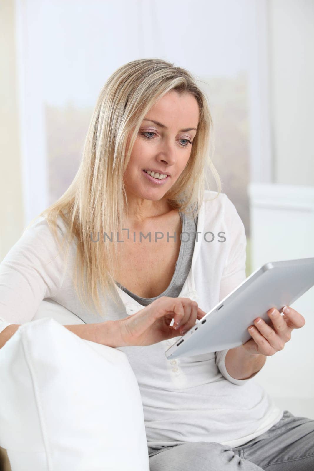 Blond woman using electronic tablet at home